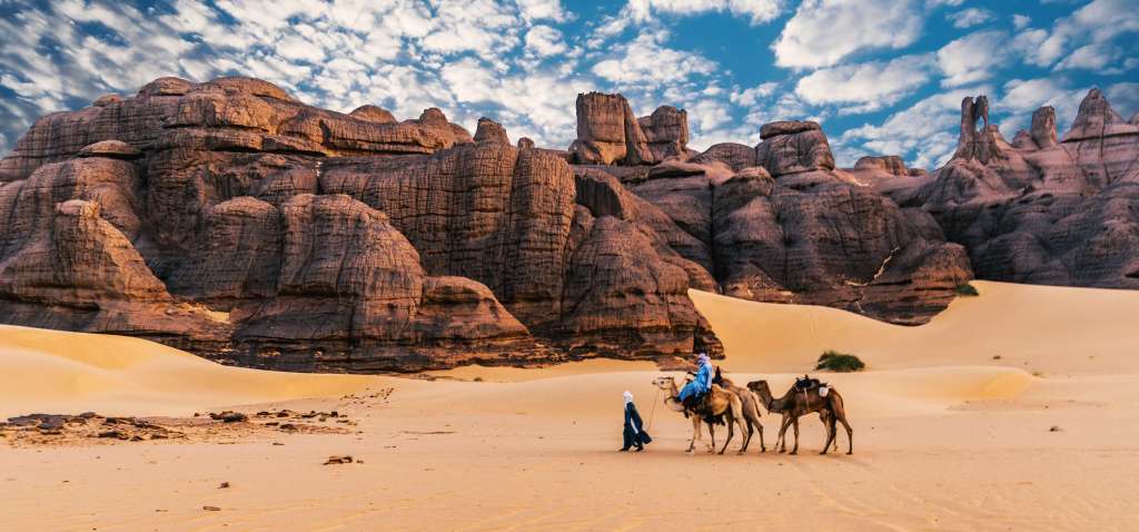trois chameau dans un désert rocheux avec deux hommes en Afrique